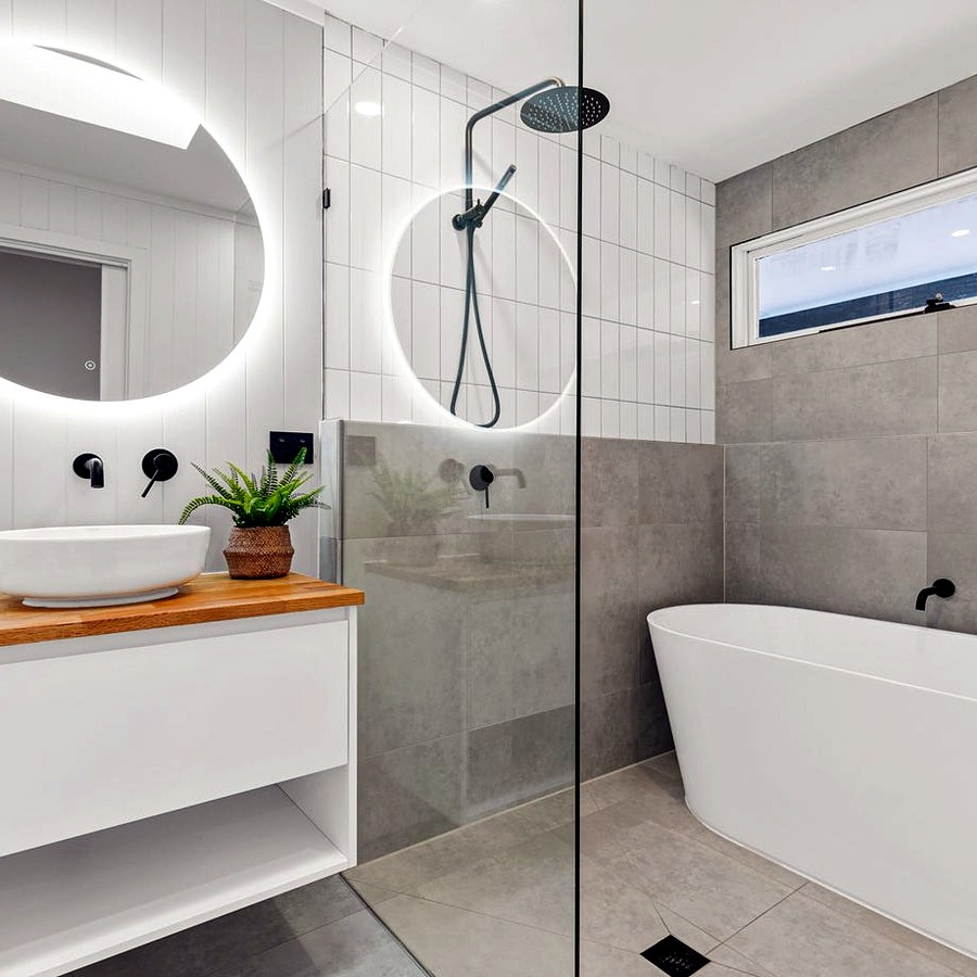 Bathroom renovation with backlit round mirrors and freestanding bath