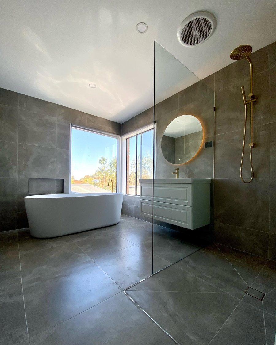 Bathroom with freestanding bath, brass tapware and large-format grey tiling