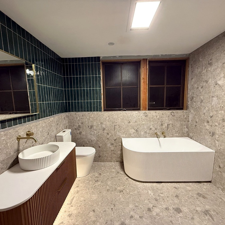 Bathroom renovation with green tile, terrazzo finish and freestanding bath