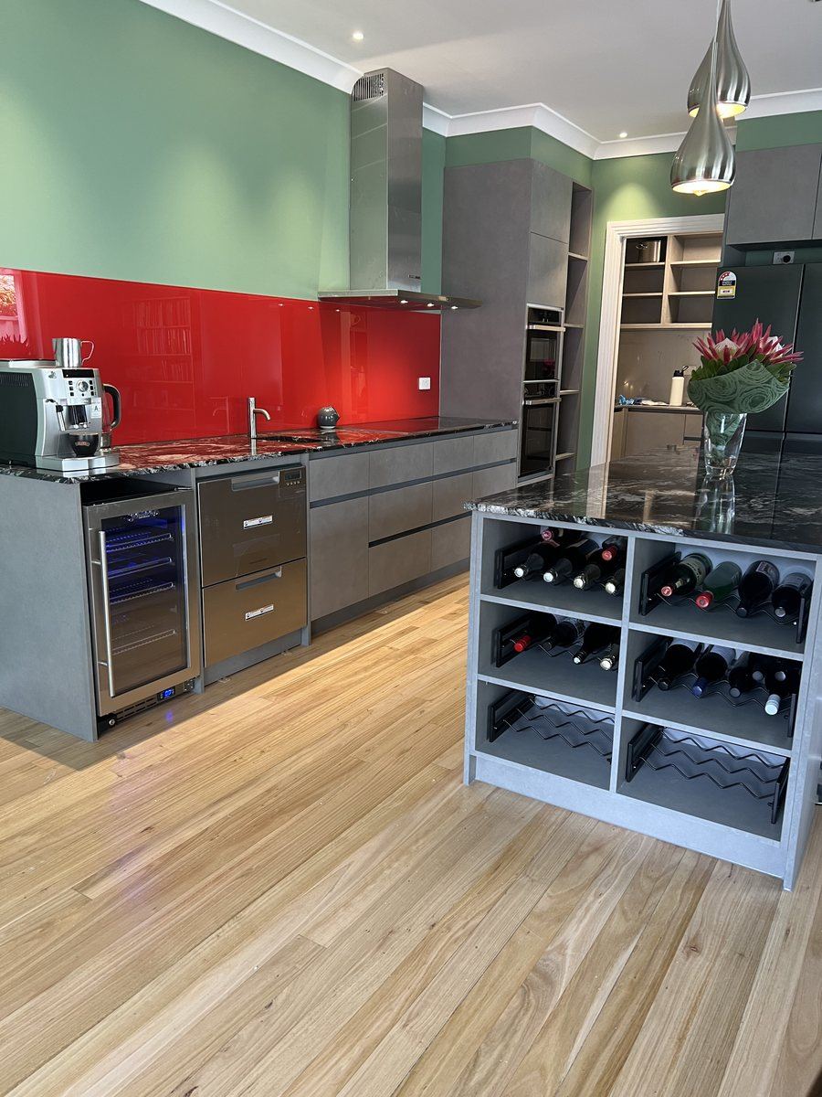 Kitchen with red splashback, green walls and built-in wine storage