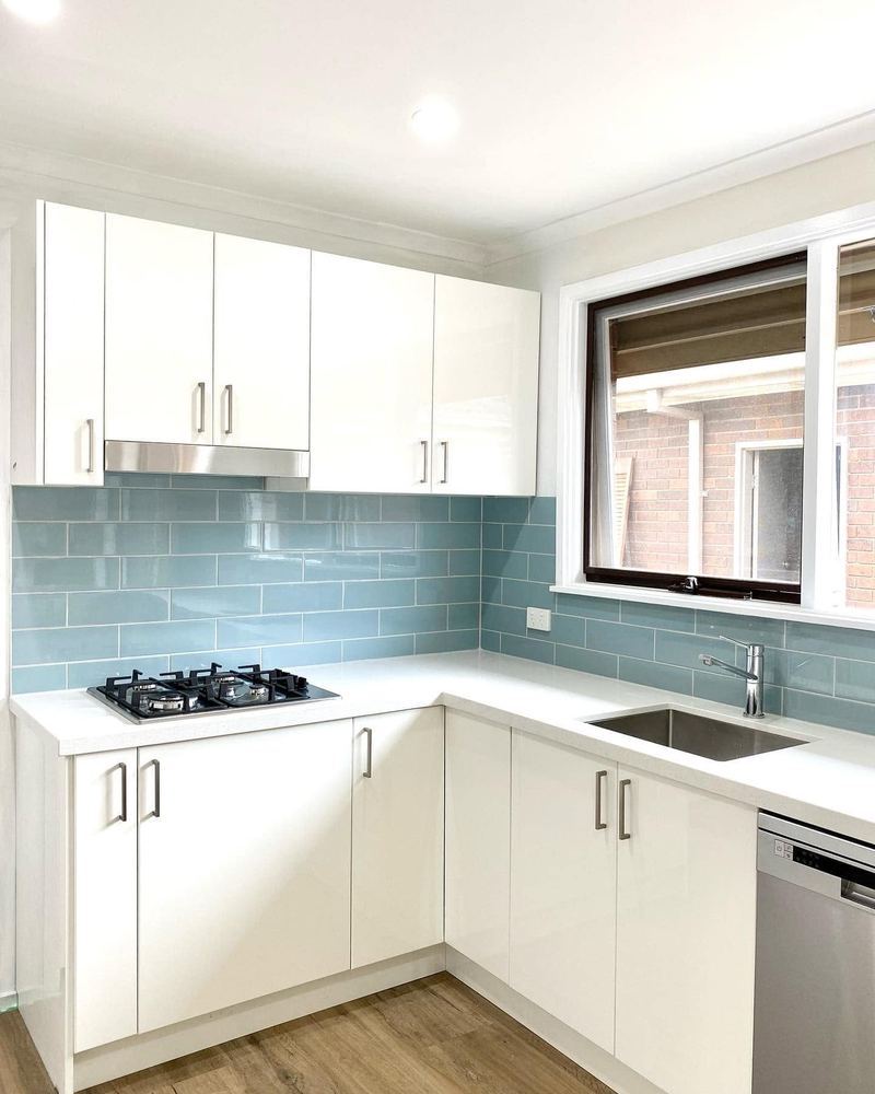 Kitchen with white cabinetry and pale subway tile splashback