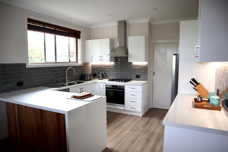 Kitchen with timber island bench and grey subway splashback