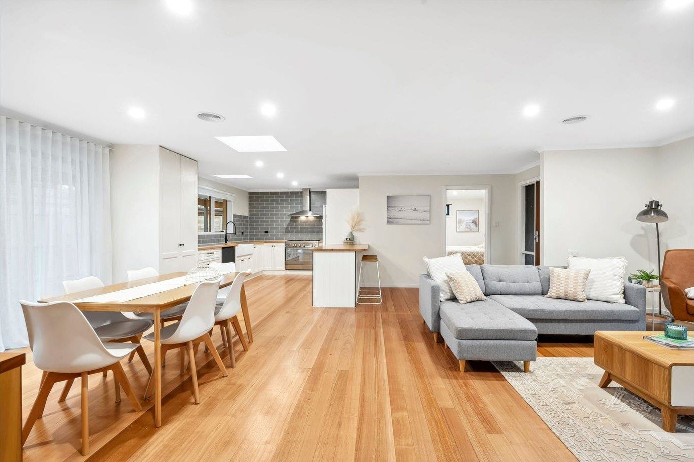 Open plan kitchen, dining and living area with timber flooring and skylights