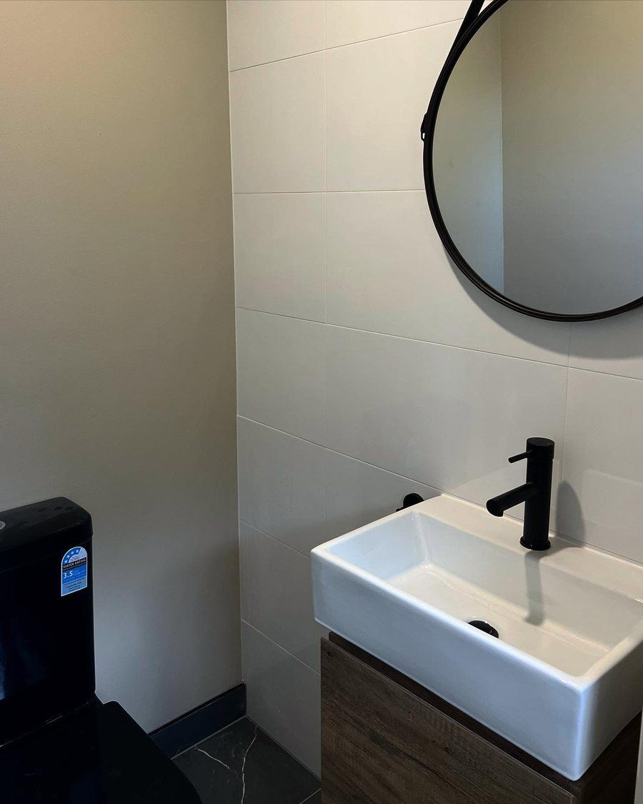 Powder room with wall-hung basin and round black mirror
